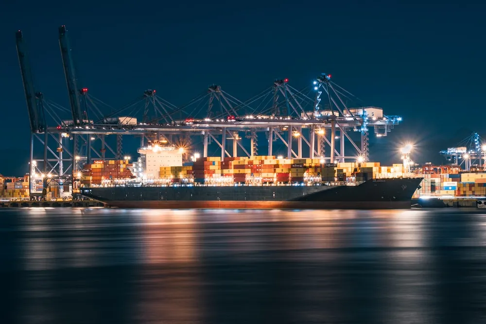 Cargo ship docked at a busy port at night.